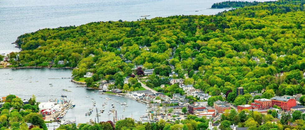 town of camden, maine from above. Lots of green trees against the water of the atlantic ocean