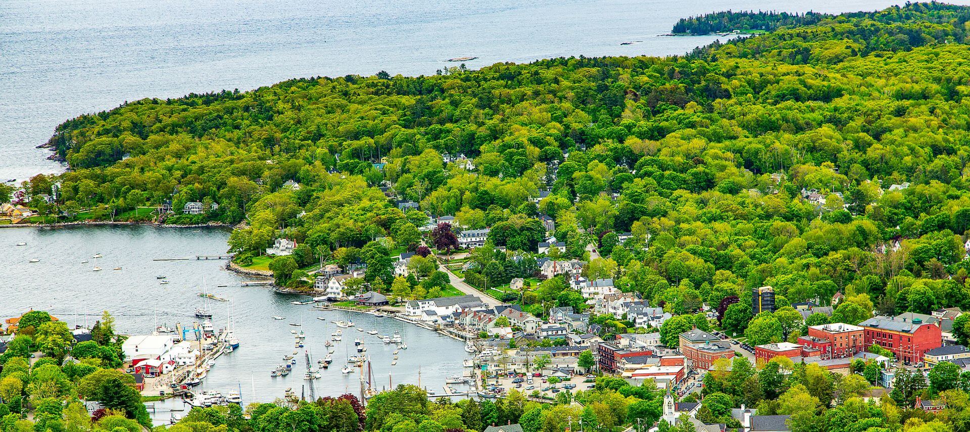 town of camden, maine from above. Lots of green trees against the water of the atlantic ocean