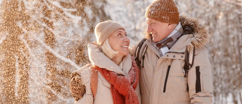 Senior couple enjoying a winter walk in the woods - one of the best things to do in Maine For Couples this winter